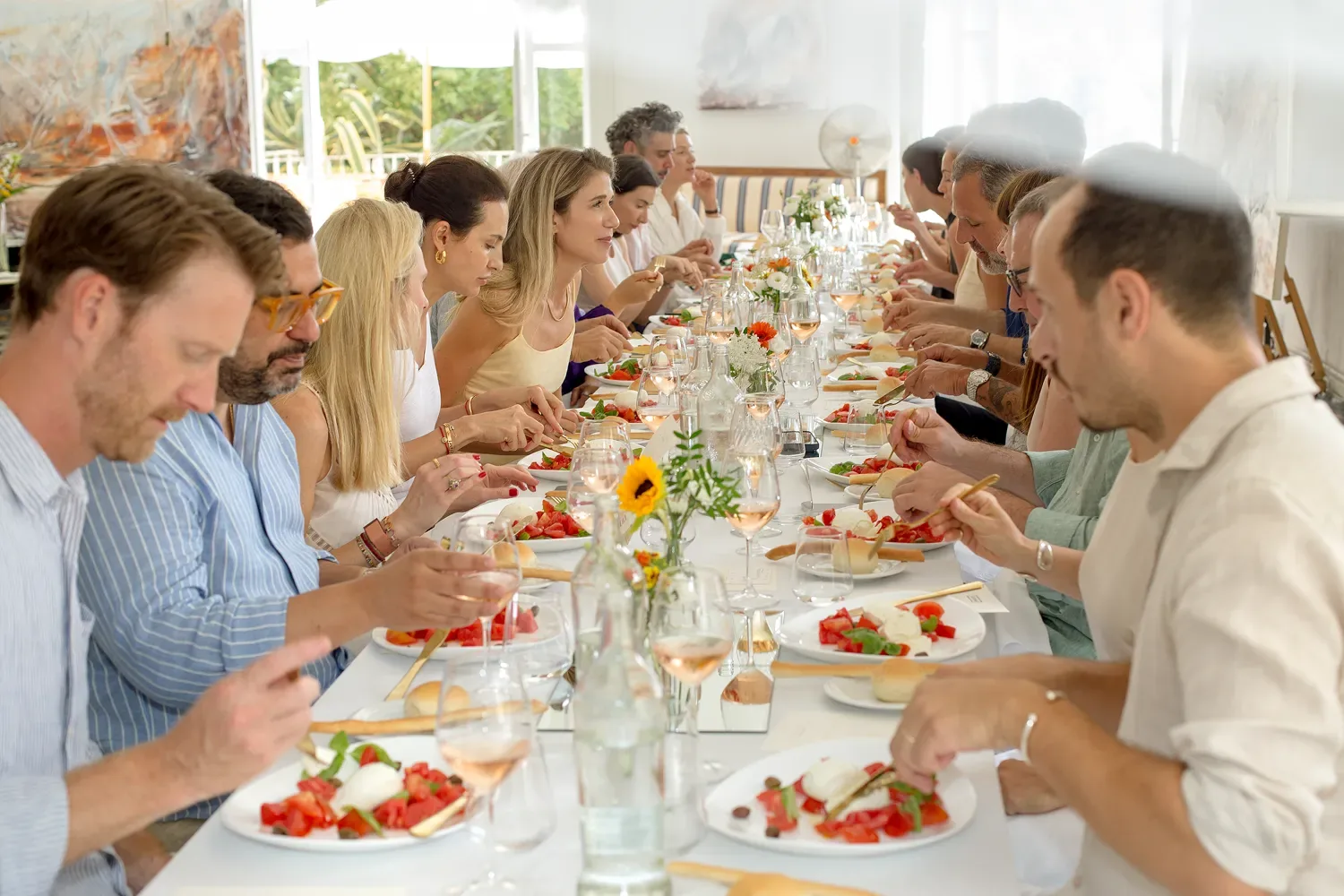 Guests at a long lunch table in the salon at Castel Caramel, at an event in honour of Kylie Manning