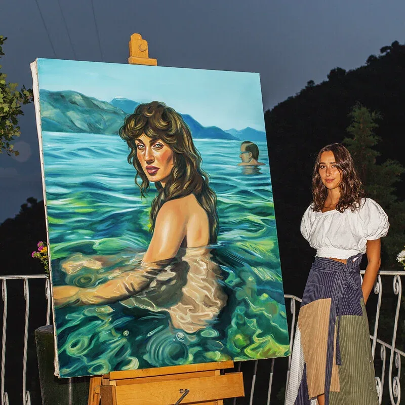 Chloe Wise beside one of her paintings on the terrace at Castel Caramel
