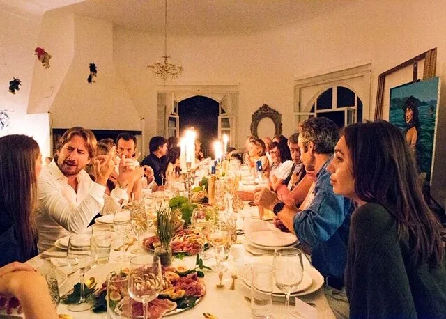Guests at a candlelit dinner in the salon at Castel Caramel