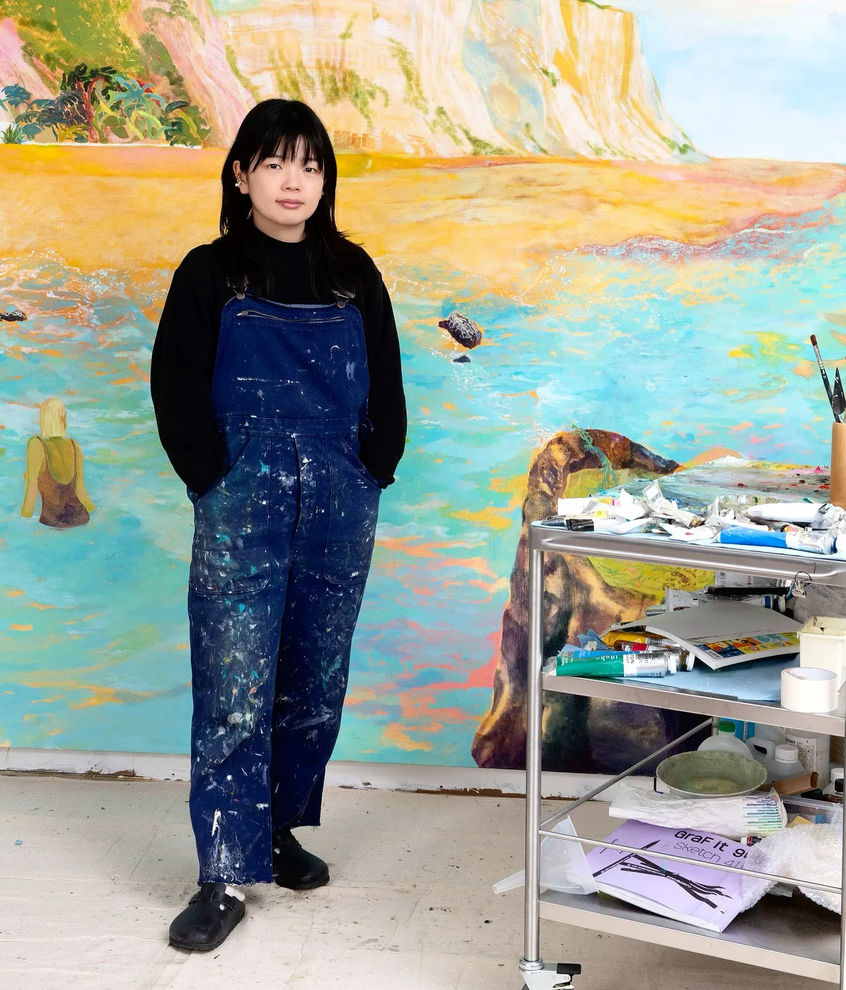 Minami Kobayashi standing in front of a painting of a coastline
